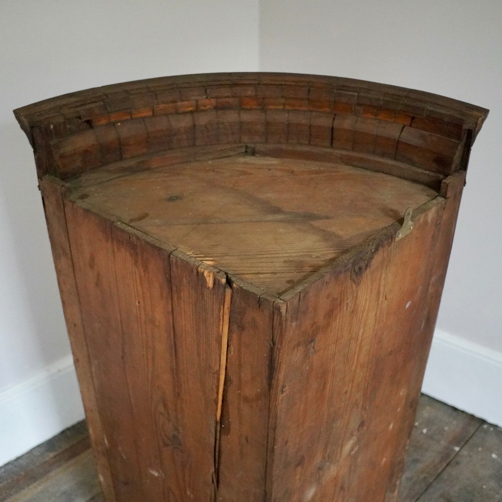 A George III bow front mahogany corner cabinet featuring polished plum pudding veneers, inlaid border stringing, and two curved doors. View XII