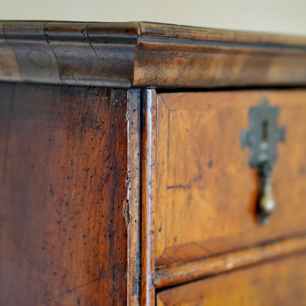 An early eighteenth-century Queen Anne walnut chest on stand featuring multiple drawers, brass teardrop handles, a shaped apron, and turned legs connected by stretchers. View IV