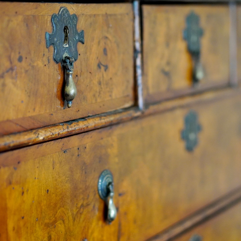 An early eighteenth-century Queen Anne walnut chest on stand featuring multiple drawers, brass teardrop handles, a shaped apron, and turned legs connected by stretchers. View V