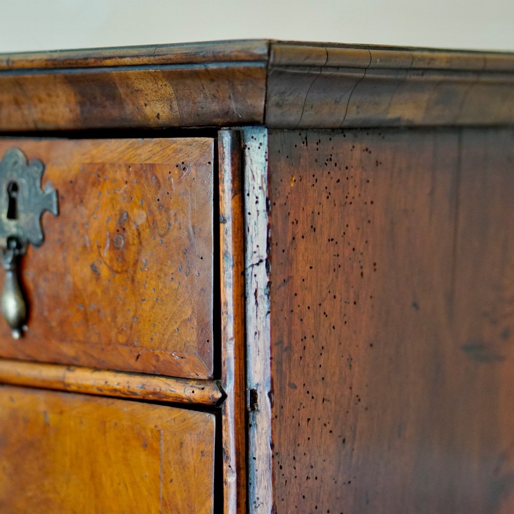 An early eighteenth-century Queen Anne walnut chest on stand featuring multiple drawers, brass teardrop handles, a shaped apron, and turned legs connected by stretchers. View VIII
