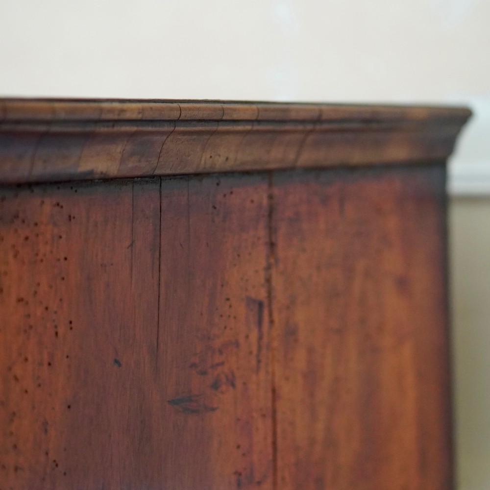 An early eighteenth-century Queen Anne walnut chest on stand featuring multiple drawers, brass teardrop handles, a shaped apron, and turned legs connected by stretchers. View IX