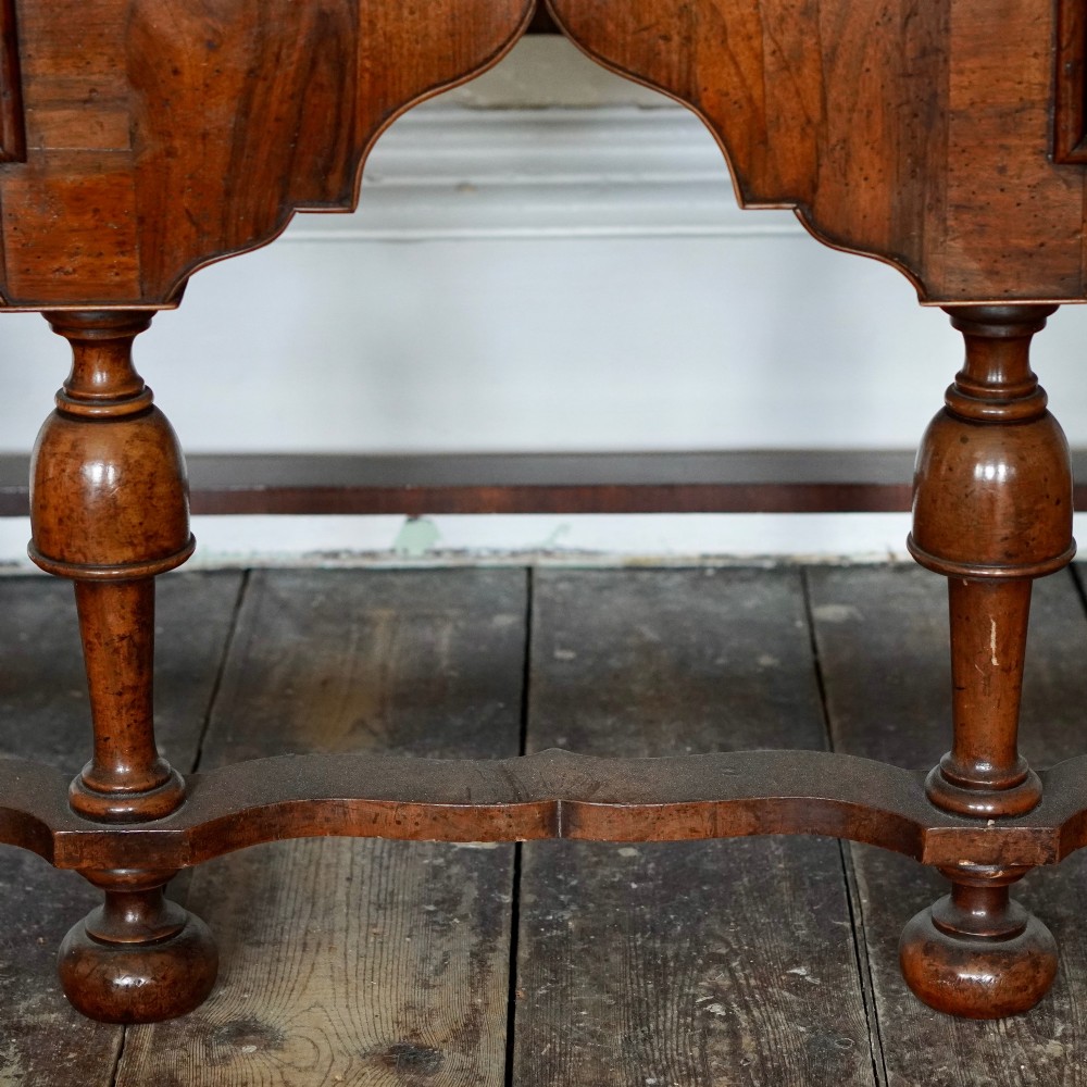 An early eighteenth-century Queen Anne walnut chest on stand featuring multiple drawers, brass teardrop handles, a shaped apron, and turned legs connected by stretchers. View X