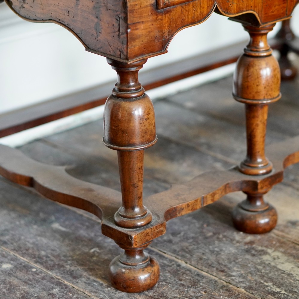An early eighteenth-century Queen Anne walnut chest on stand featuring multiple drawers, brass teardrop handles, a shaped apron, and turned legs connected by stretchers. View XI