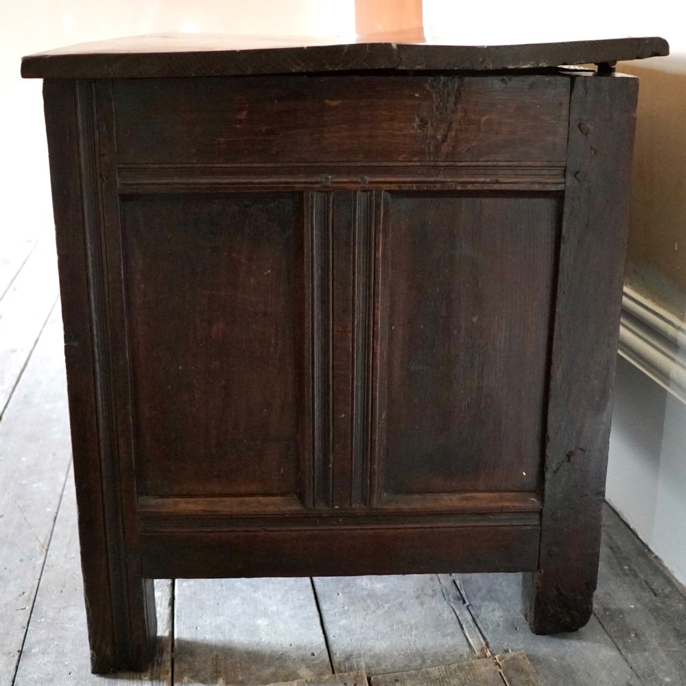 A 17th-century joined oak coffer featuring carved arch front panels, a carved top frieze, hinged lid, and brass keyhole escutcheon. View IV