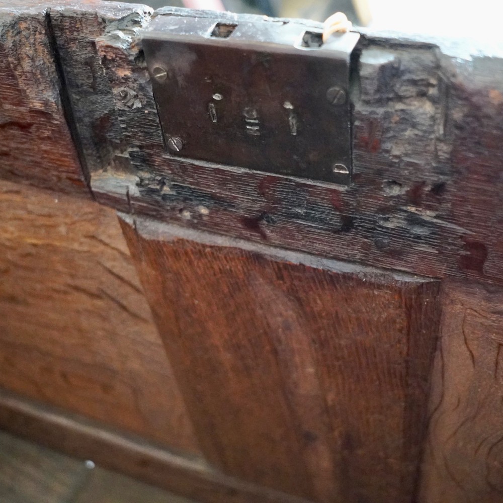 A 17th-century joined oak coffer featuring carved arch front panels, a carved top frieze, hinged lid, and brass keyhole escutcheon. View VIII