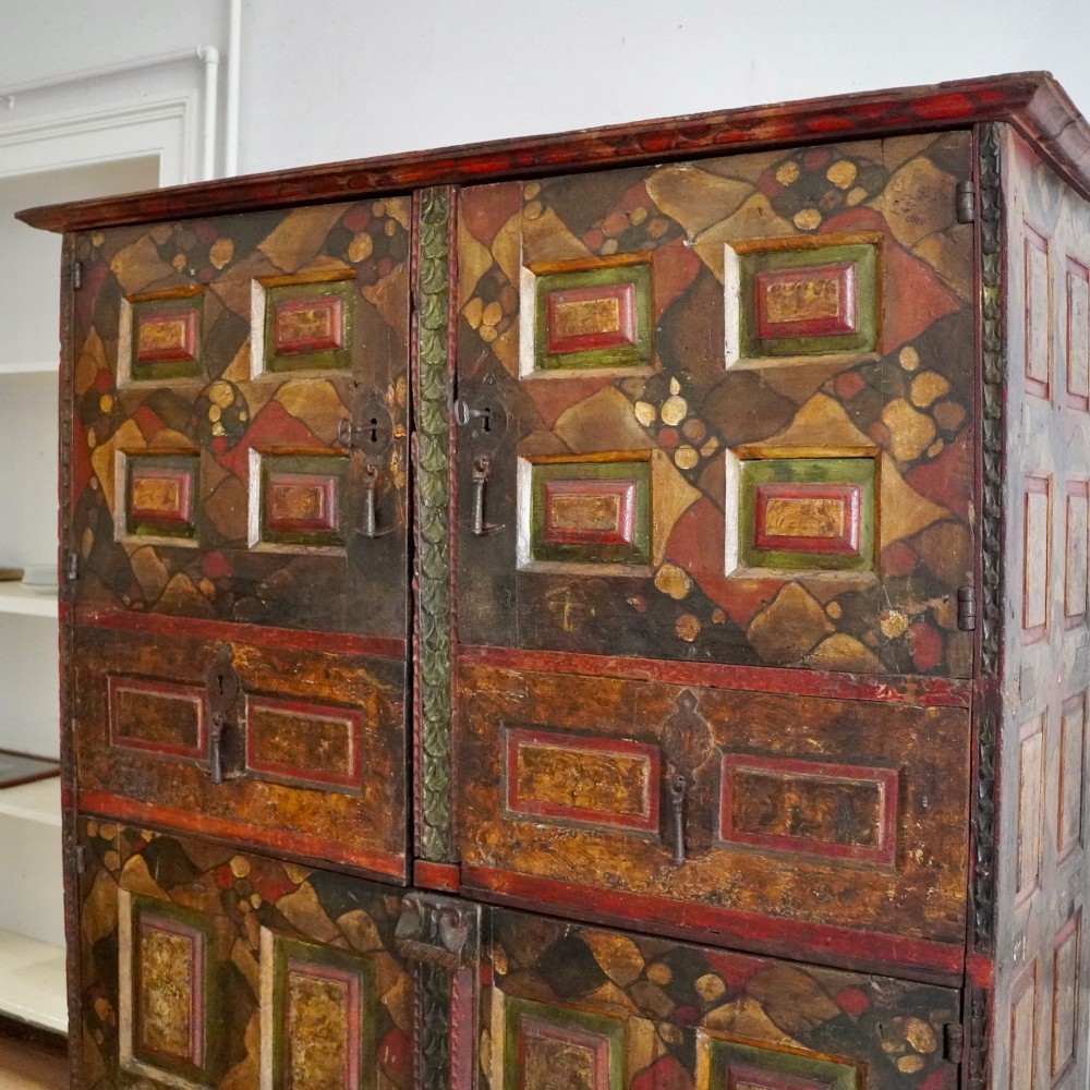 A tall seventeenth-century Spanish oak press cupboard featuring double upper and lower doors decorated with geometric raised panels and painted polychrome geometric patterns. View II