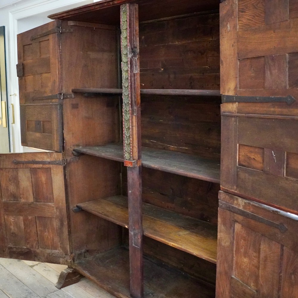 A tall seventeenth-century Spanish oak press cupboard featuring double upper and lower doors decorated with geometric raised panels and painted polychrome geometric patterns. View XII