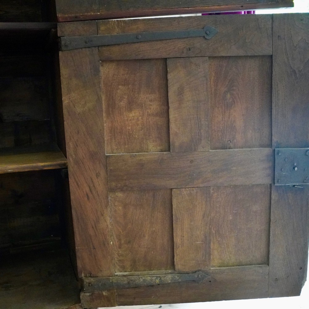 A tall seventeenth-century Spanish oak press cupboard featuring double upper and lower doors decorated with geometric raised panels and painted polychrome geometric patterns. View XIII