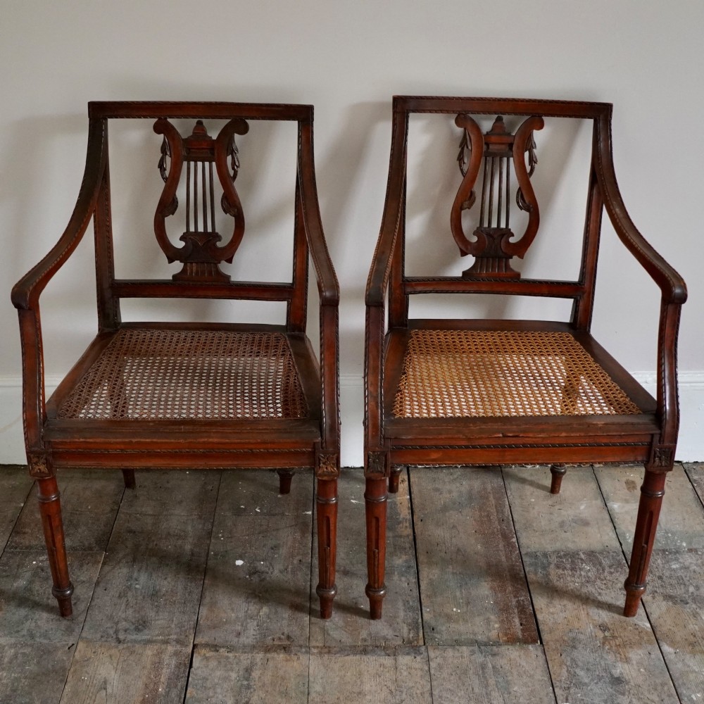 A matching pair of 19th-century Regency style mahogany armchairs featuring carved lyre back splats and woven cane seats. View II