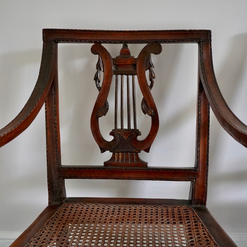 A matching pair of 19th-century Regency style mahogany armchairs featuring carved lyre back splats and woven cane seats. View III
