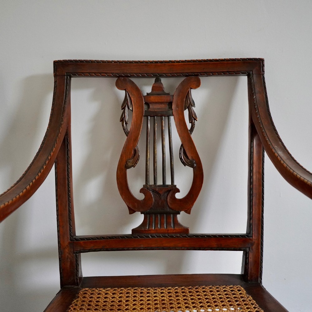 A matching pair of 19th-century Regency style mahogany armchairs featuring carved lyre back splats and woven cane seats. View IV