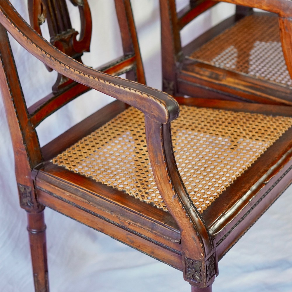 A matching pair of 19th-century Regency style mahogany armchairs featuring carved lyre back splats and woven cane seats. View VI