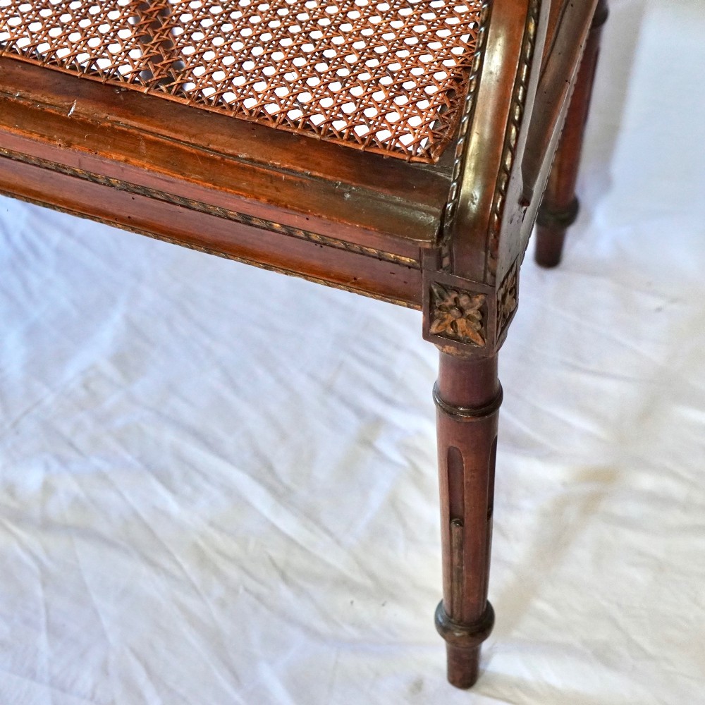A matching pair of 19th-century Regency style mahogany armchairs featuring carved lyre back splats and woven cane seats. View IX