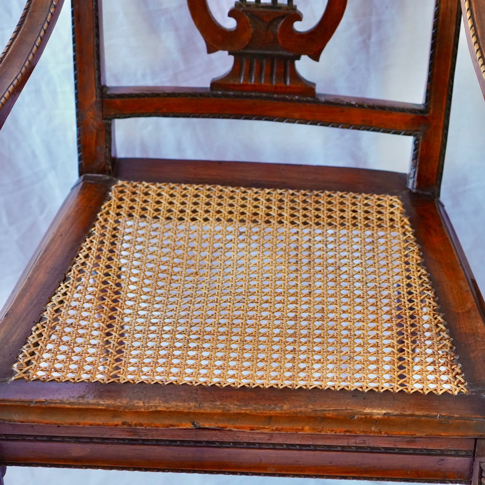 A matching pair of 19th-century Regency style mahogany armchairs featuring carved lyre back splats and woven cane seats. View XI