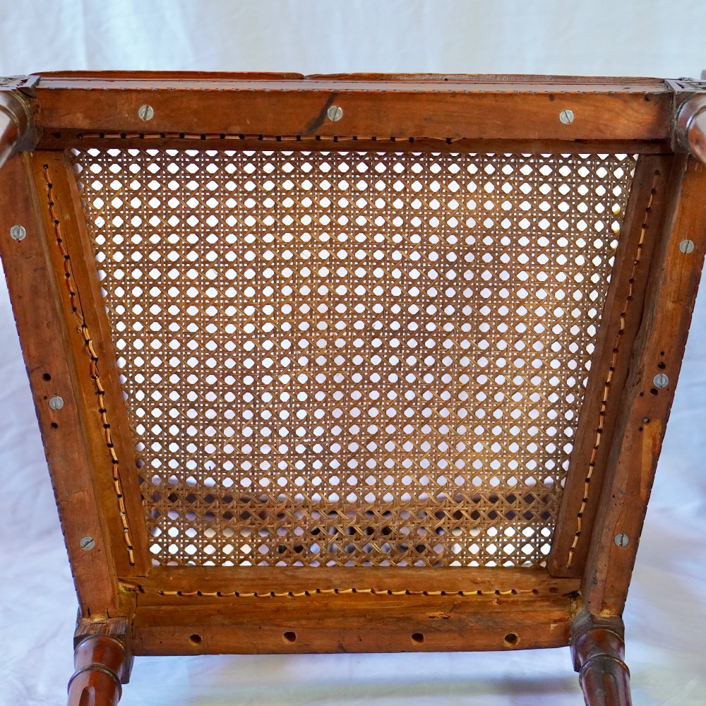 A matching pair of 19th-century Regency style mahogany armchairs featuring carved lyre back splats and woven cane seats. View XIV
