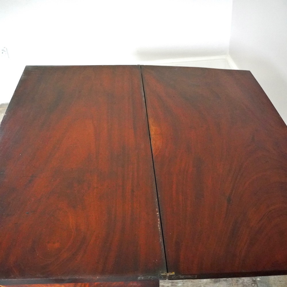 A Victorian figured mahogany card table featuring a turnover top, carved frieze, turned pedestal, and scroll legs with castors. View X