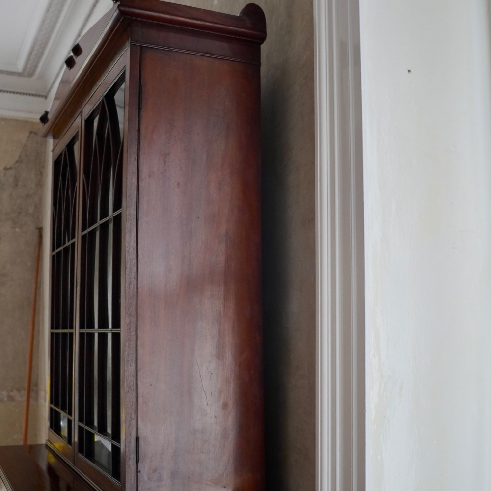 A nineteenth-century George IV mahogany secretaire bookcase with glazed upper doors featuring gothic tracery and a drop-down desk drawer revealing a fitted interior. View IV