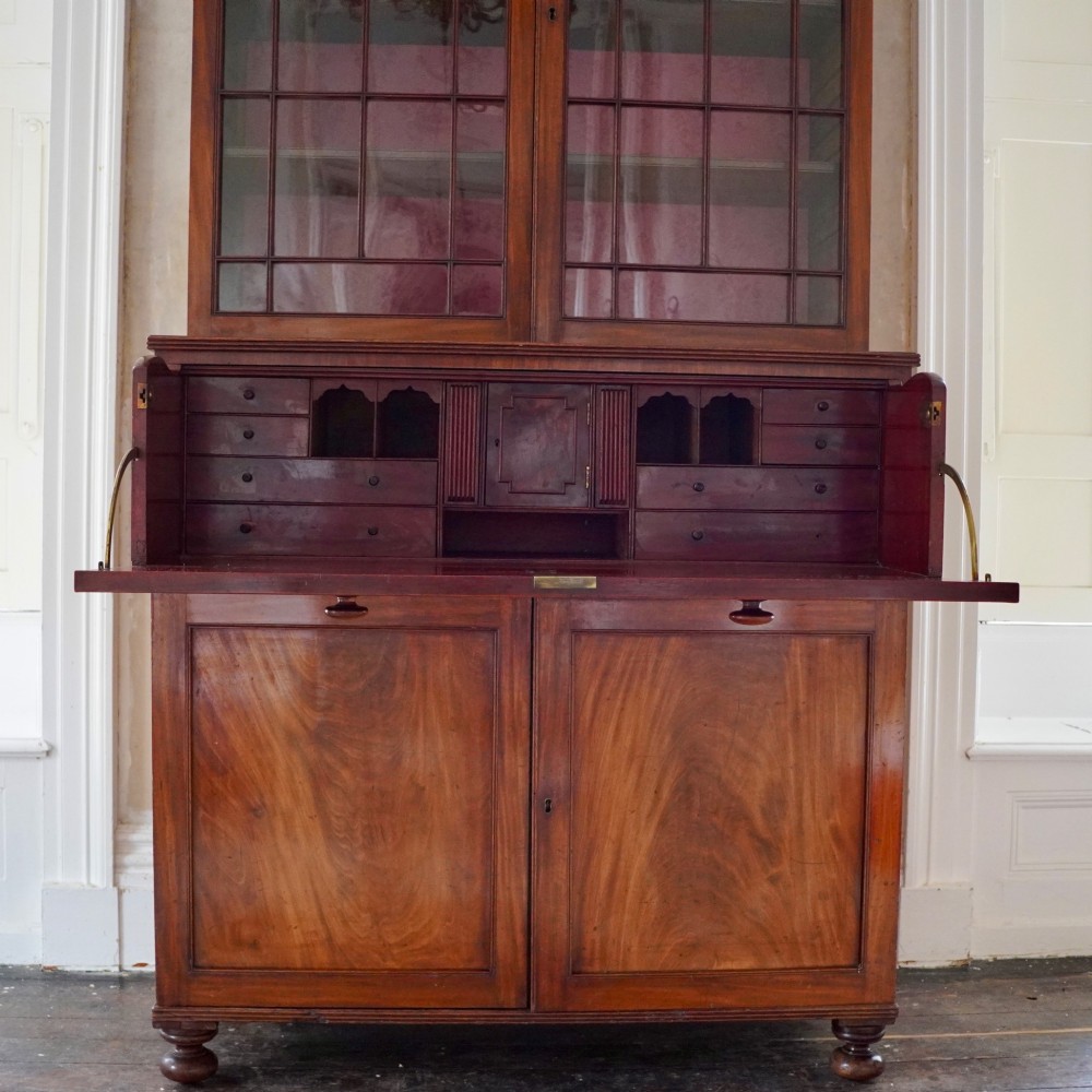 A nineteenth-century George IV mahogany secretaire bookcase with glazed upper doors featuring gothic tracery and a drop-down desk drawer revealing a fitted interior. View X