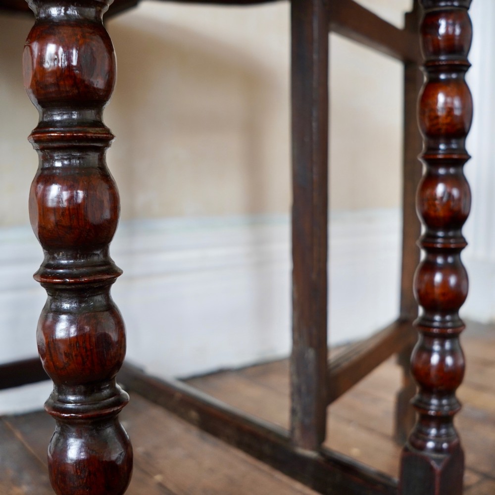 A dark brown antique oak gateleg drop-leaf table with turned legs and an oval top. View II