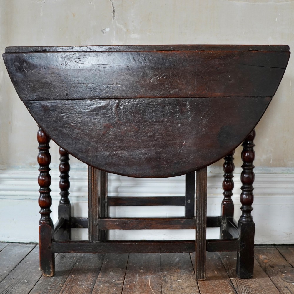A dark brown antique oak gateleg drop-leaf table with turned legs and an oval top. View III
