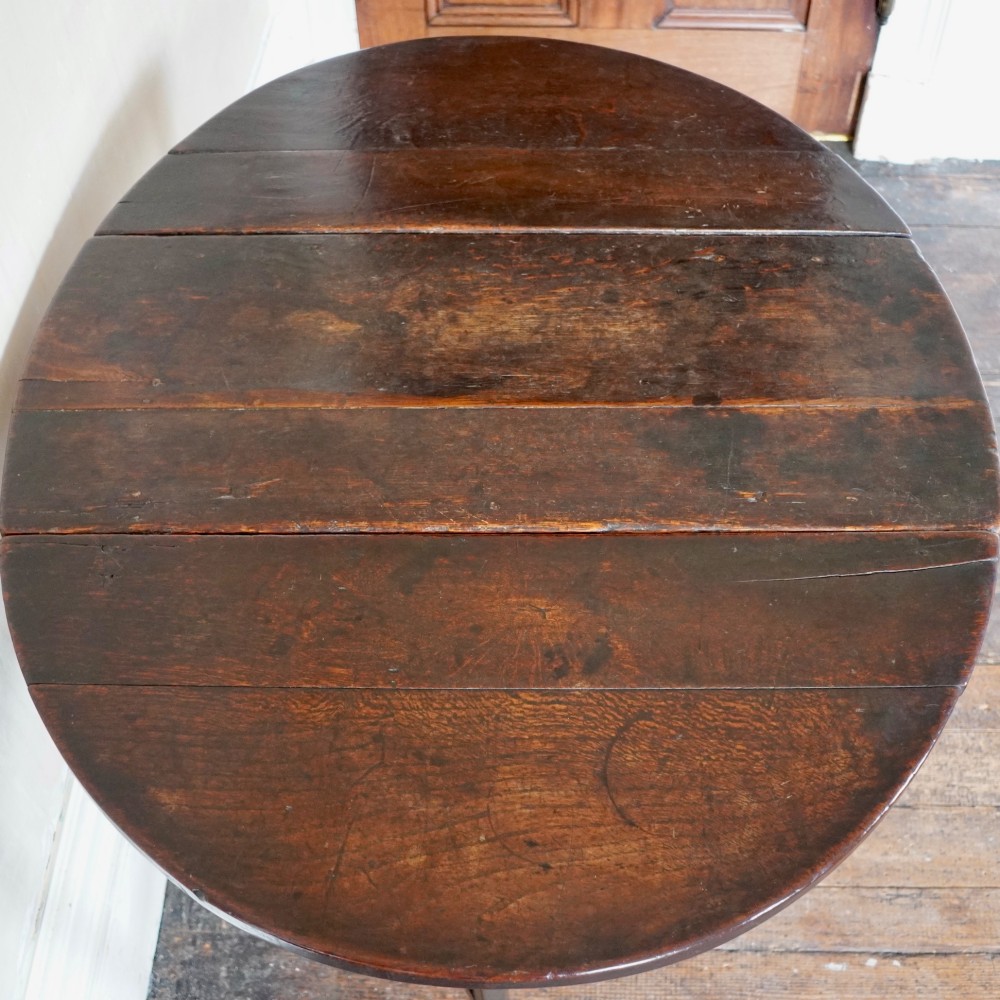 A dark brown antique oak gateleg drop-leaf table with turned legs and an oval top. View VII