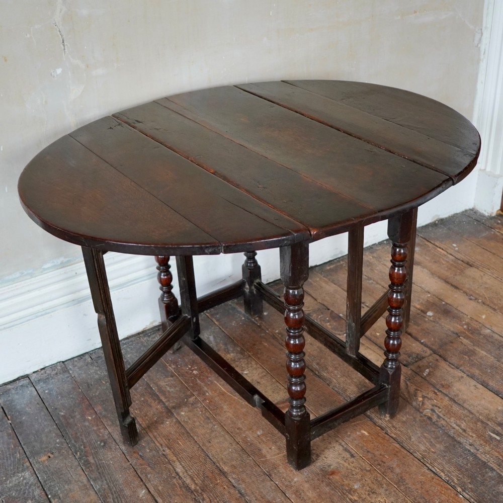A dark brown antique oak gateleg drop-leaf table with turned legs and an oval top. View VIII