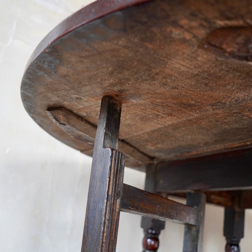 A dark brown antique oak gateleg drop-leaf table with turned legs and an oval top. View XII