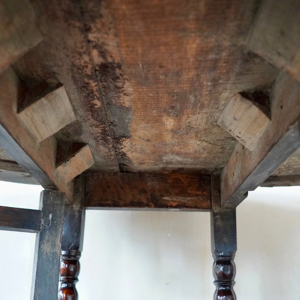 A dark brown antique oak gateleg drop-leaf table with turned legs and an oval top. View XIII