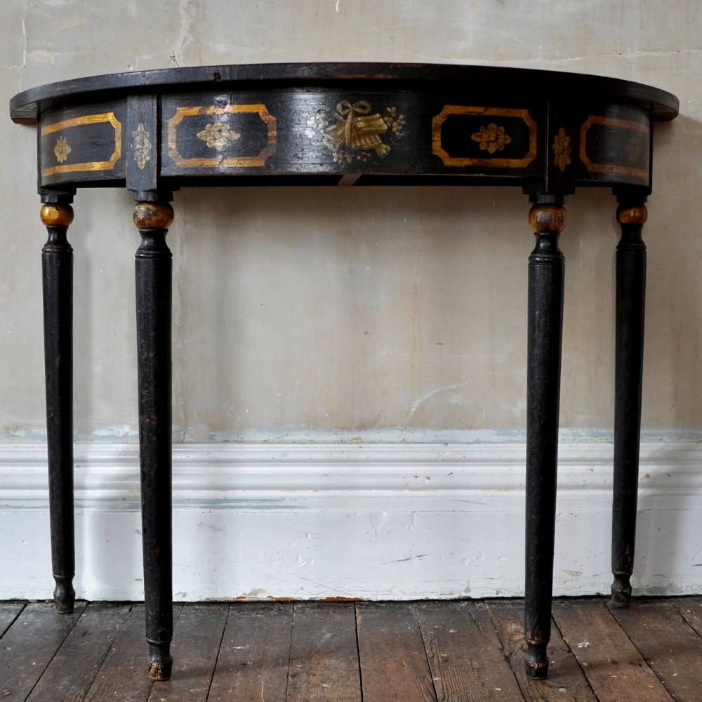 A Regency period semi-circular console table painted black with gold-gilded classical panel motifs and four slender turned legs. View IV