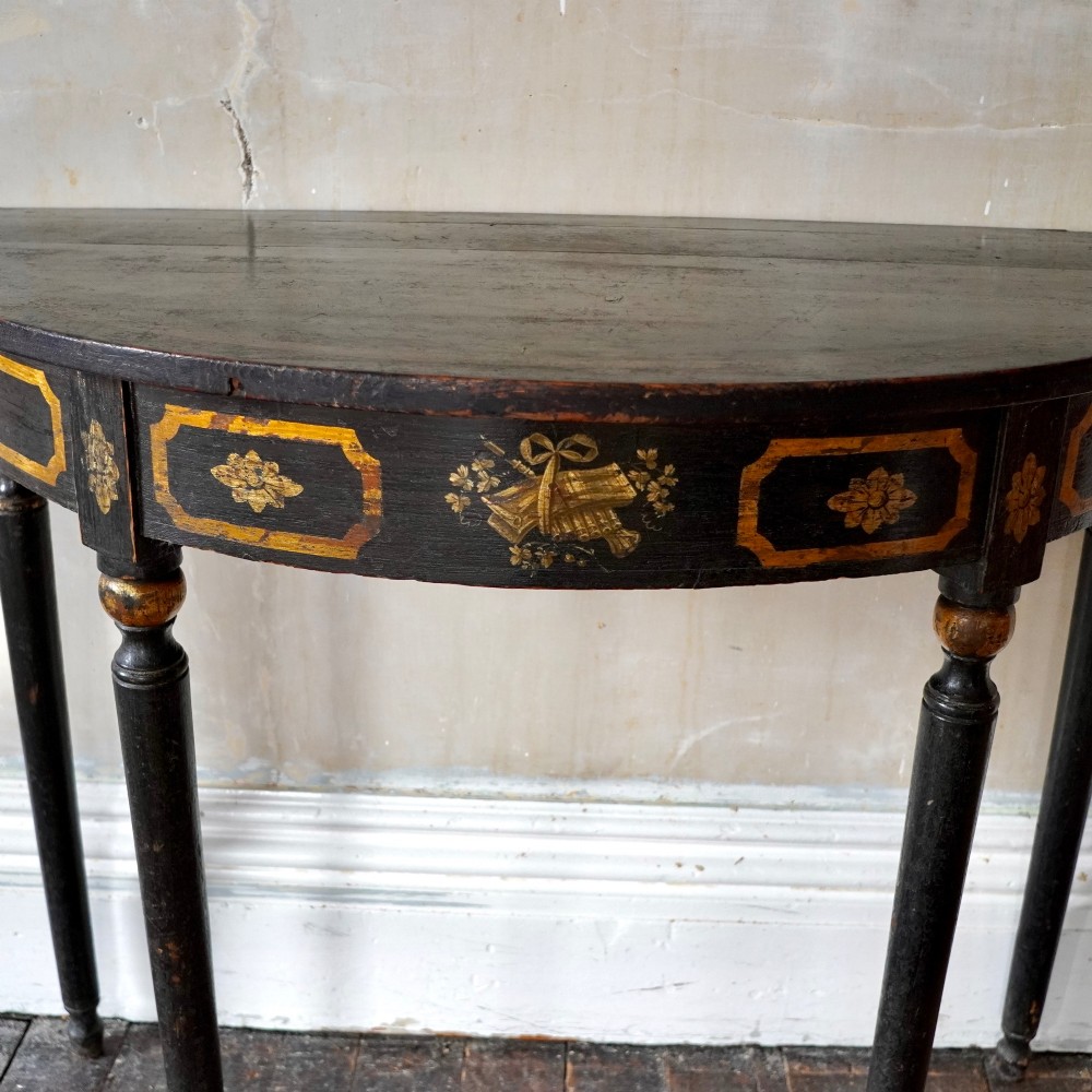 A Regency period semi-circular console table painted black with gold-gilded classical panel motifs and four slender turned legs. View VII