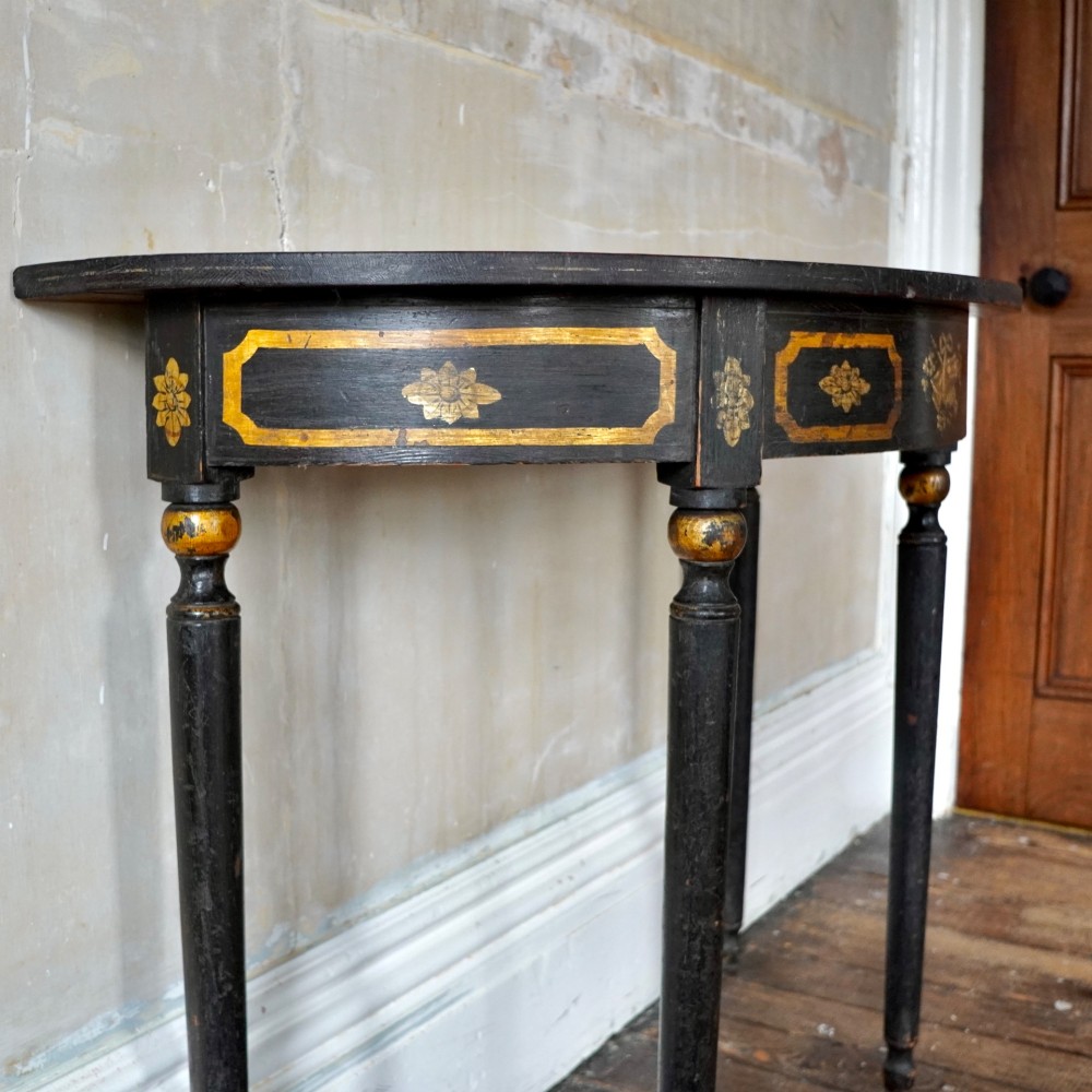 A Regency period semi-circular console table painted black with gold-gilded classical panel motifs and four slender turned legs. View IX