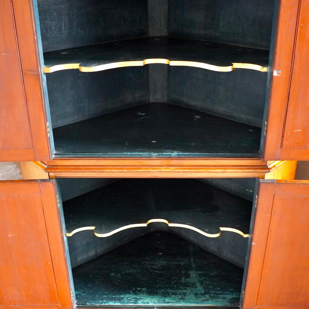 A tall, two-tier William IV corner cupboard crafted from dark plum pudding mahogany, featuring panelled double doors on both top and bottom sections with carved detail and a pediment top. View II