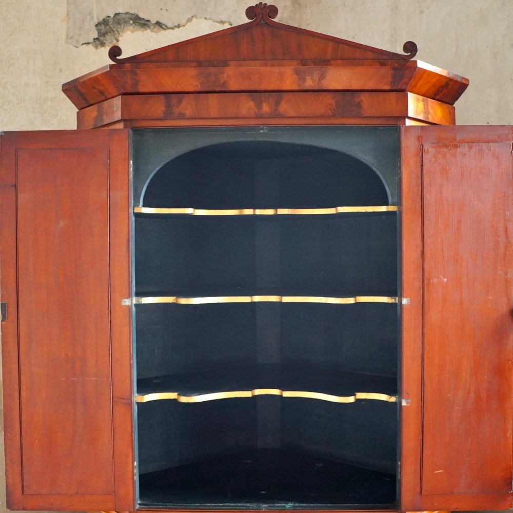 A tall, two-tier William IV corner cupboard crafted from dark plum pudding mahogany, featuring panelled double doors on both top and bottom sections with carved detail and a pediment top. View III