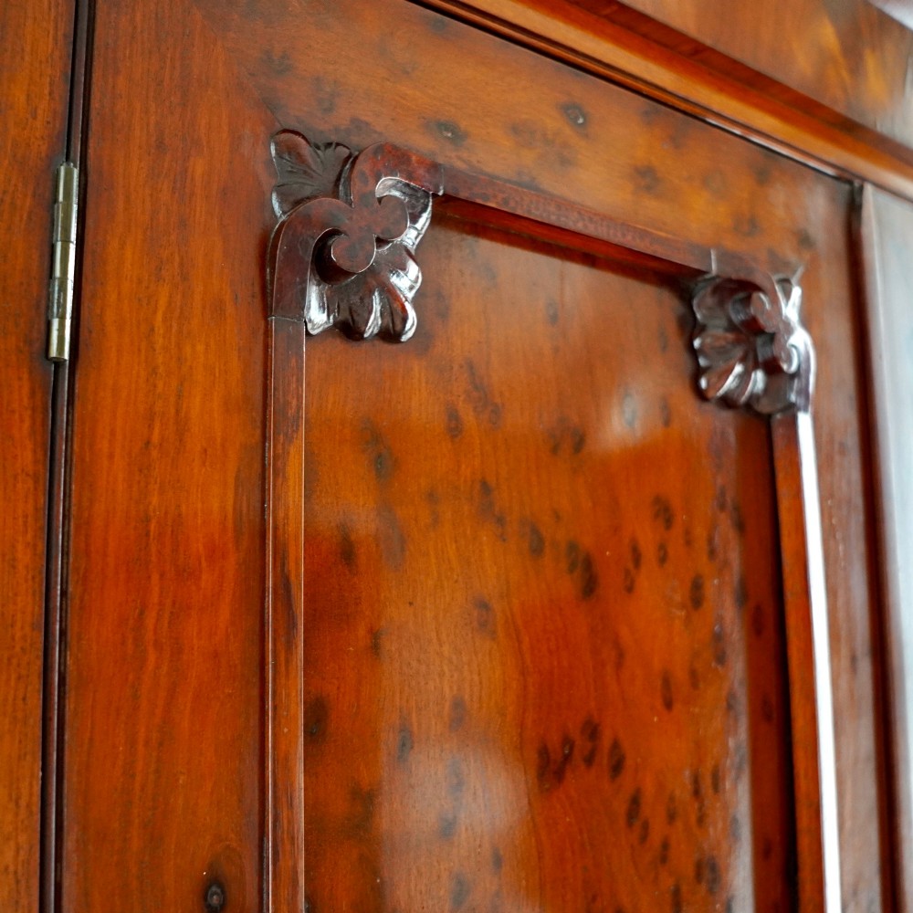 A tall, two-tier William IV corner cupboard crafted from dark plum pudding mahogany, featuring panelled double doors on both top and bottom sections with carved detail and a pediment top. View VII