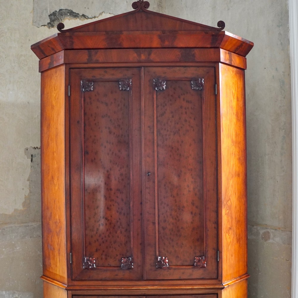 A tall, two-tier William IV corner cupboard crafted from dark plum pudding mahogany, featuring panelled double doors on both top and bottom sections with carved detail and a pediment top. View VIII