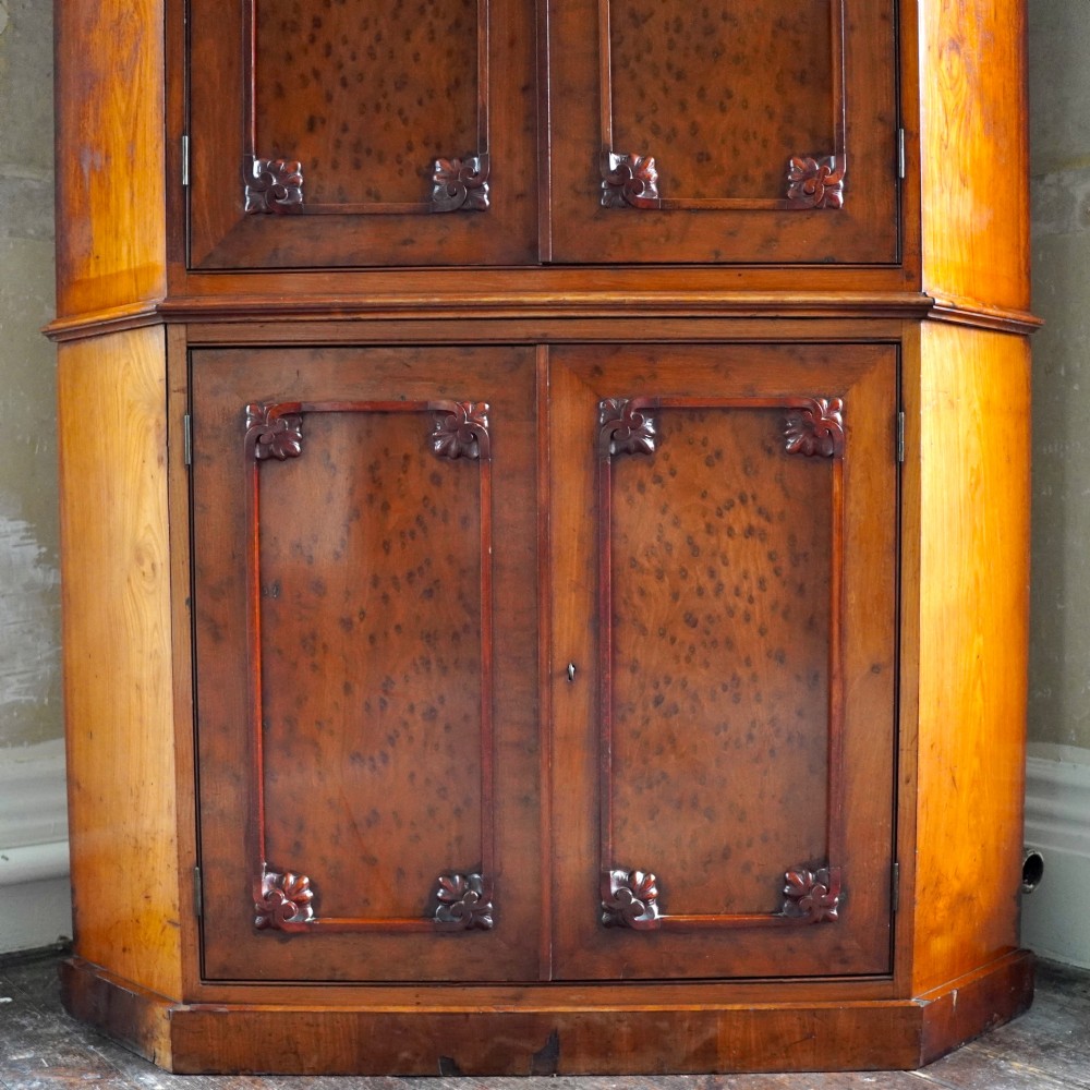 A tall, two-tier William IV corner cupboard crafted from dark plum pudding mahogany, featuring panelled double doors on both top and bottom sections with carved detail and a pediment top. View IX