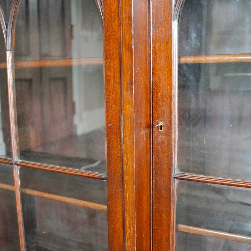 A large Victorian dark mahogany breakfront glazed bookcase featuring three doors with Gothic arch astragal glazing bars and a fluted cornice. View IV