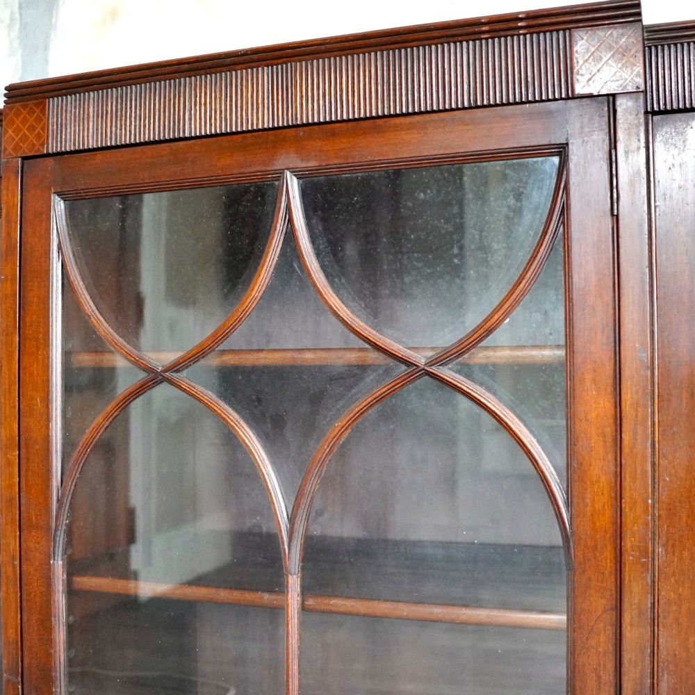 A large Victorian dark mahogany breakfront glazed bookcase featuring three doors with Gothic arch astragal glazing bars and a fluted cornice. View V