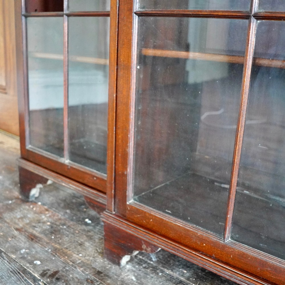 A large Victorian dark mahogany breakfront glazed bookcase featuring three doors with Gothic arch astragal glazing bars and a fluted cornice. View VI