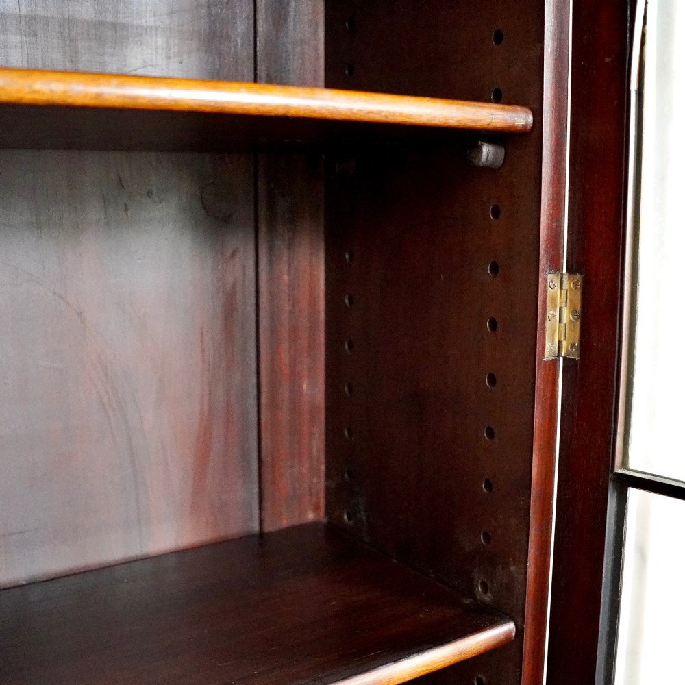 A large Victorian dark mahogany breakfront glazed bookcase featuring three doors with Gothic arch astragal glazing bars and a fluted cornice. View VIII
