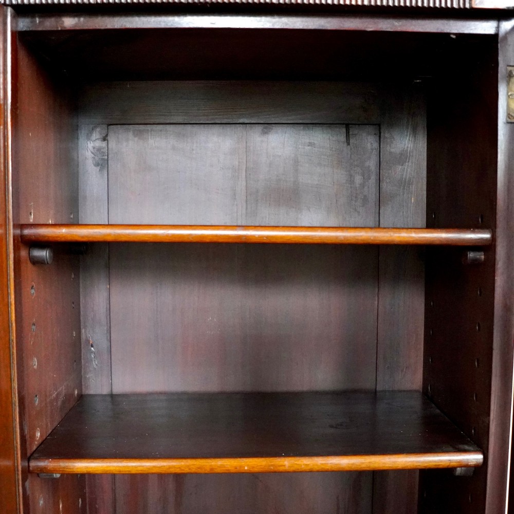 A large Victorian dark mahogany breakfront glazed bookcase featuring three doors with Gothic arch astragal glazing bars and a fluted cornice. View IX