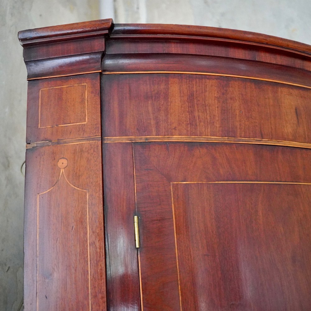 A tall Georgian mahogany bowfront corner cupboard featuring two upper curved doors, two lower curved doors, and fine line inlay. View VI
