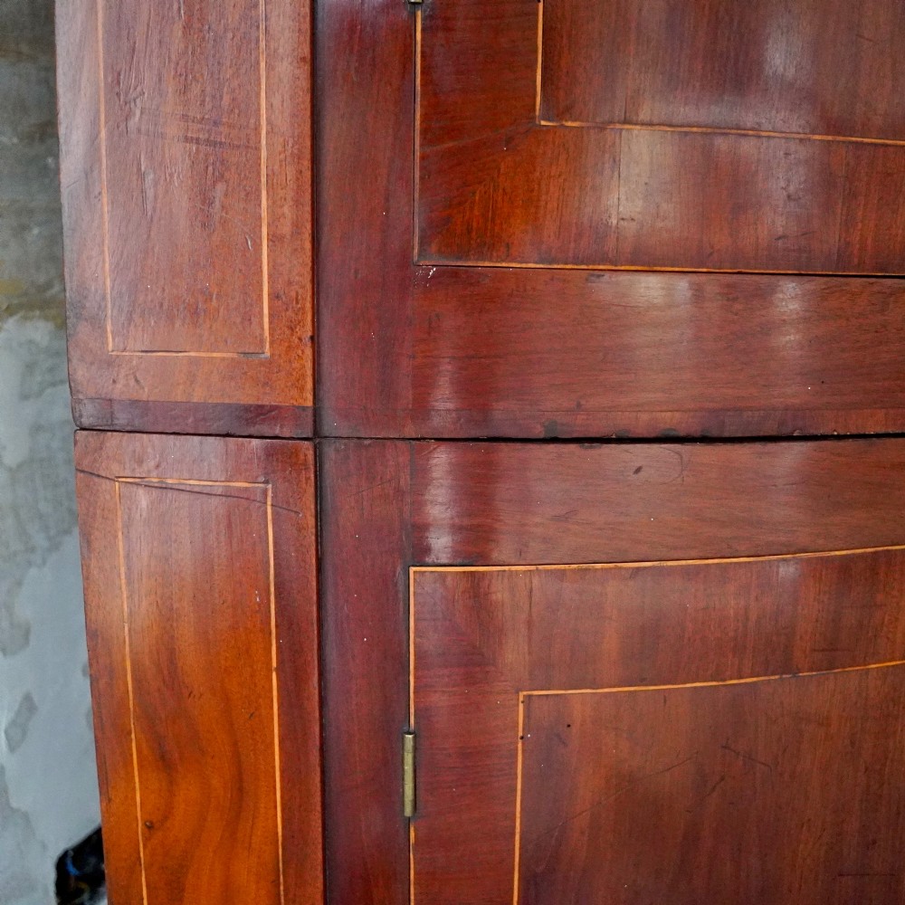 A tall Georgian mahogany bowfront corner cupboard featuring two upper curved doors, two lower curved doors, and fine line inlay. View XI