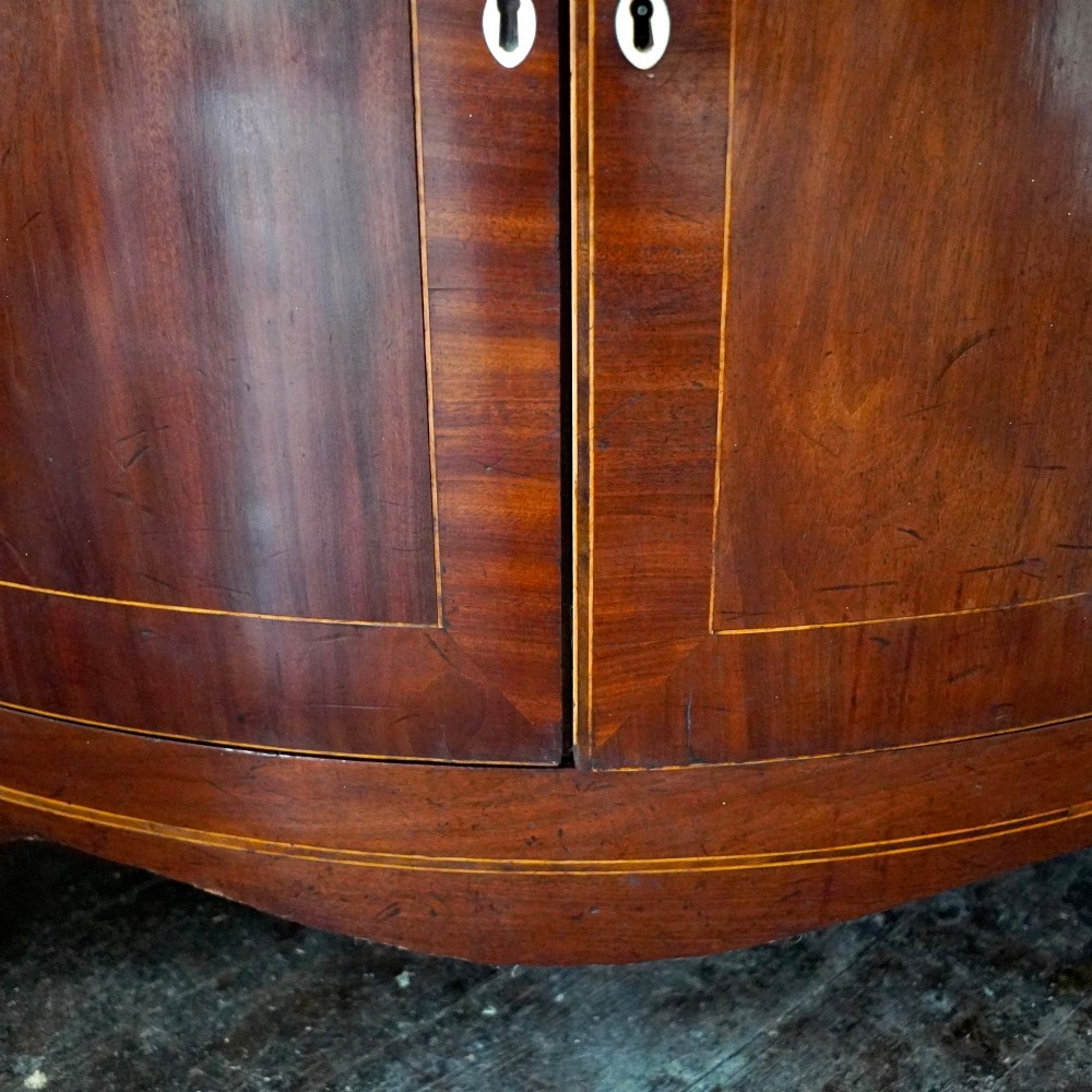 A tall Georgian mahogany bowfront corner cupboard featuring two upper curved doors, two lower curved doors, and fine line inlay. View XIII
