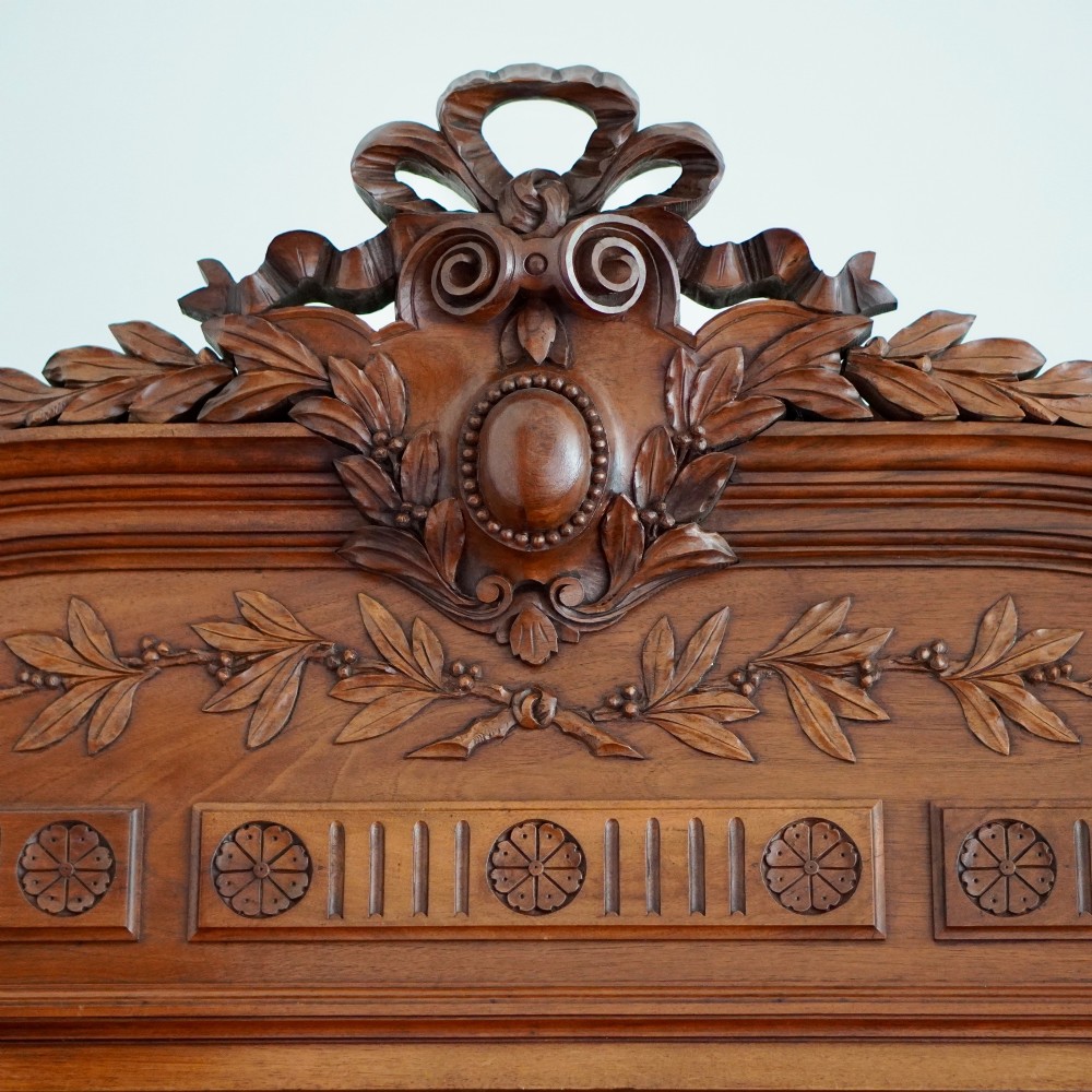 A tall 19th-century Continental open wooden bookcase featuring an ornate carved pediment, fluted side columns, panelled back, and multiple adjustable shelves. View II