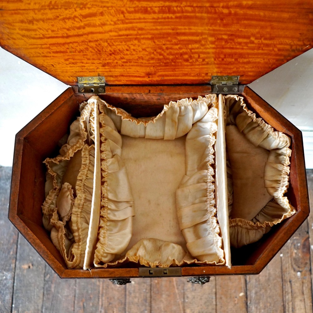 An octagonal George III satinwood work table with two drawers, lion mask ring handles, and tapered legs ending in brass castors. View VI