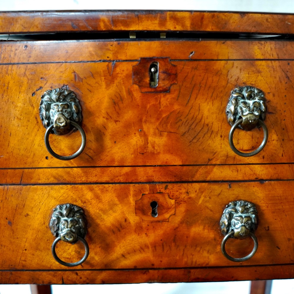An octagonal George III satinwood work table with two drawers, lion mask ring handles, and tapered legs ending in brass castors. View VIII