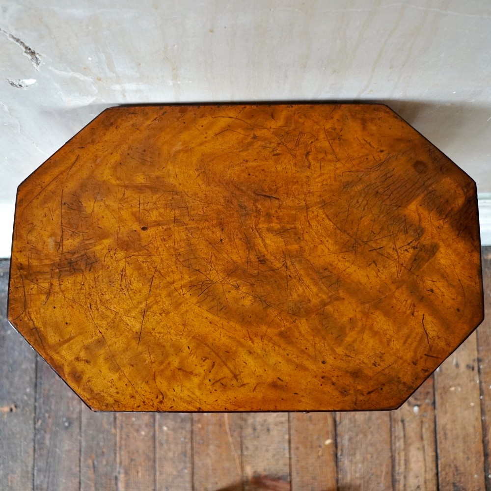 An octagonal George III satinwood work table with two drawers, lion mask ring handles, and tapered legs ending in brass castors. View XII