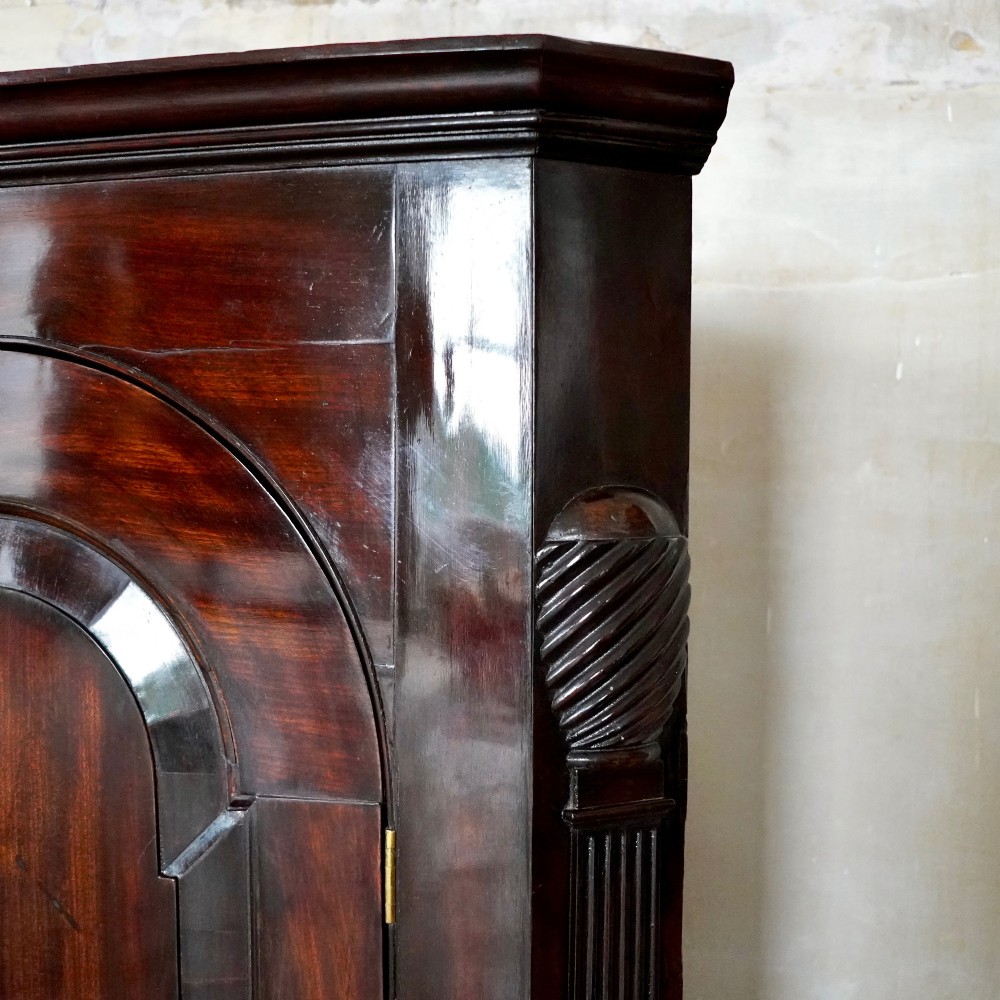 Mid-18th century Georgian mahogany hanging corner cupboard featuring an arched panelled door, brass hardware, and fluted pilasters. View IX