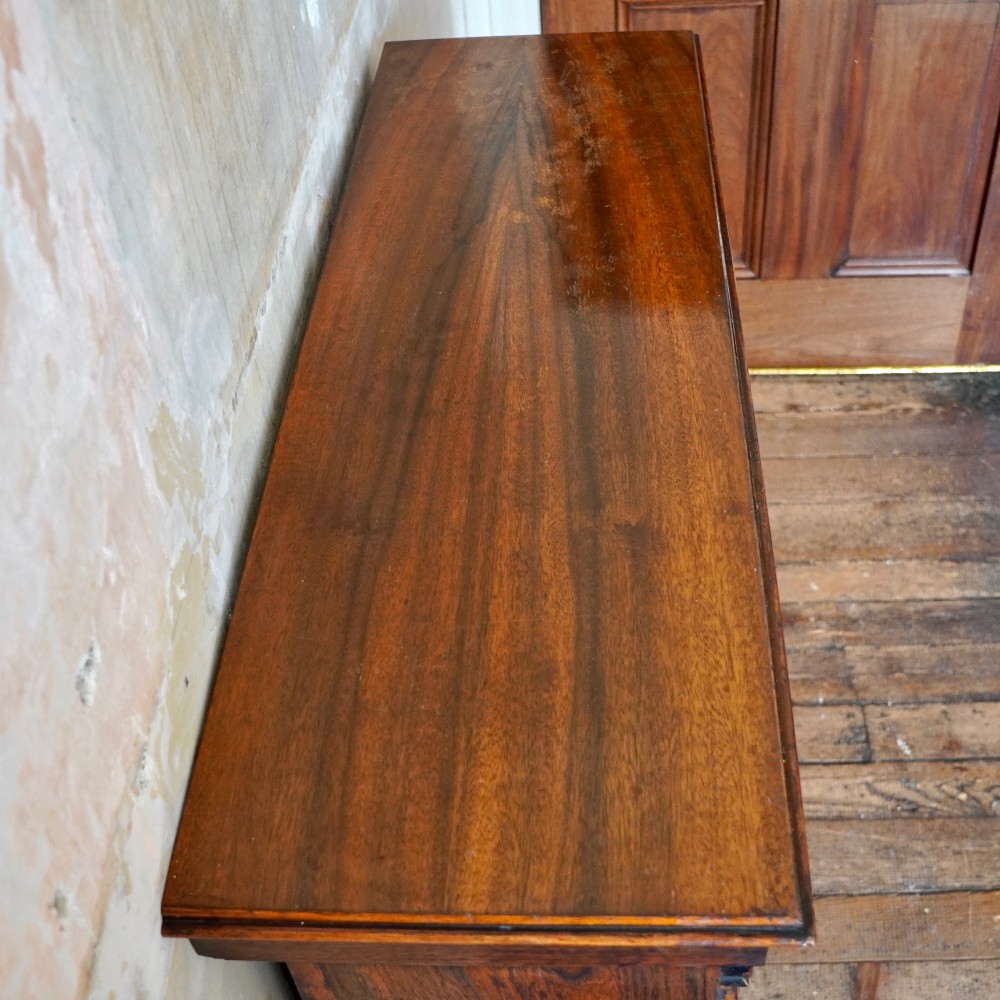An antique William IV rosewood open bookcase featuring two adjustable shelves, a solid plinth base, and carved scroll capitals atop side pilasters. View VII